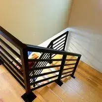 Black horizontal bar steel stair railing with a matching landing guard in a home interior